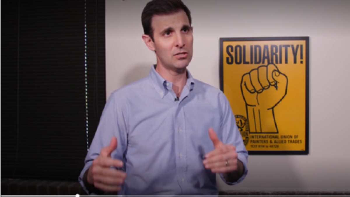 Rep. Deluzio stands in front of a sign that says "Solidarity!"