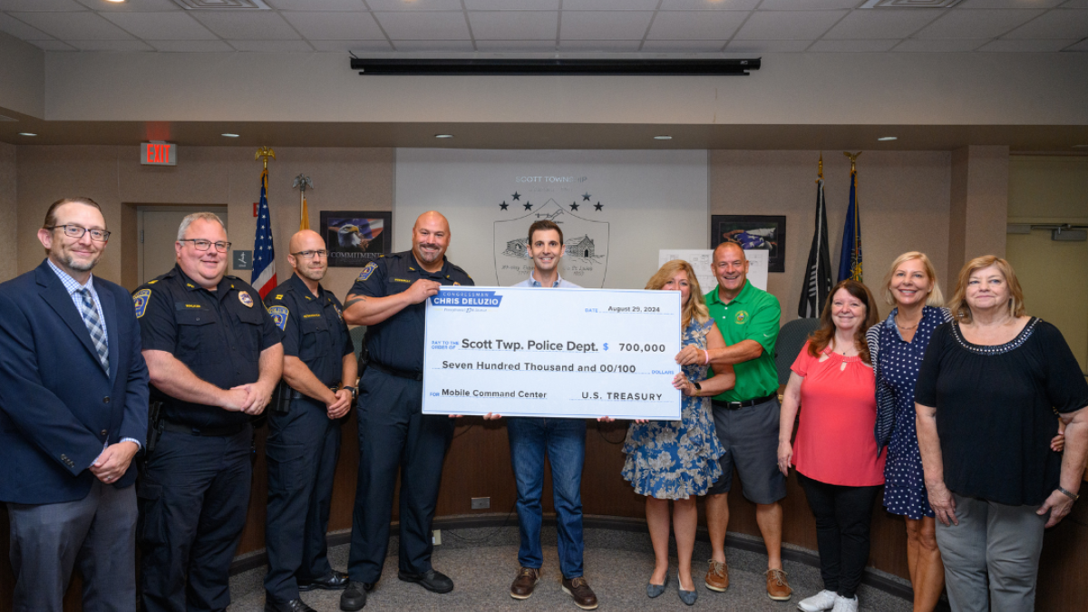 Ten people gather around a large check for a photo. 