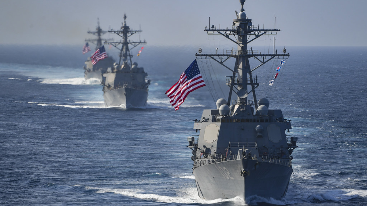 three naval ships sail on the ocean with american flags