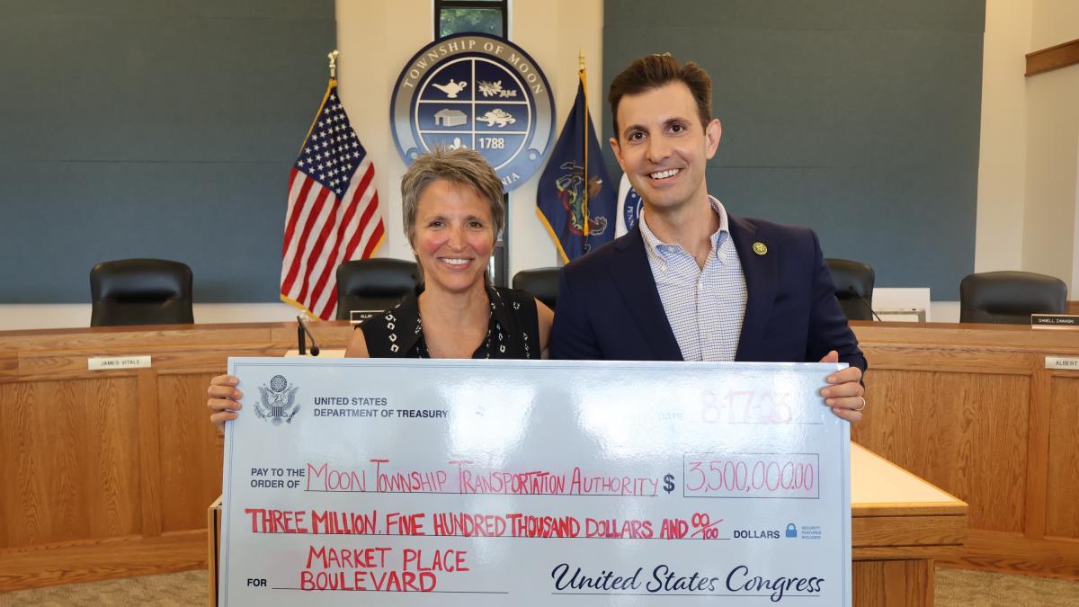 Rep. Deluzio holds a large check alongside a woman