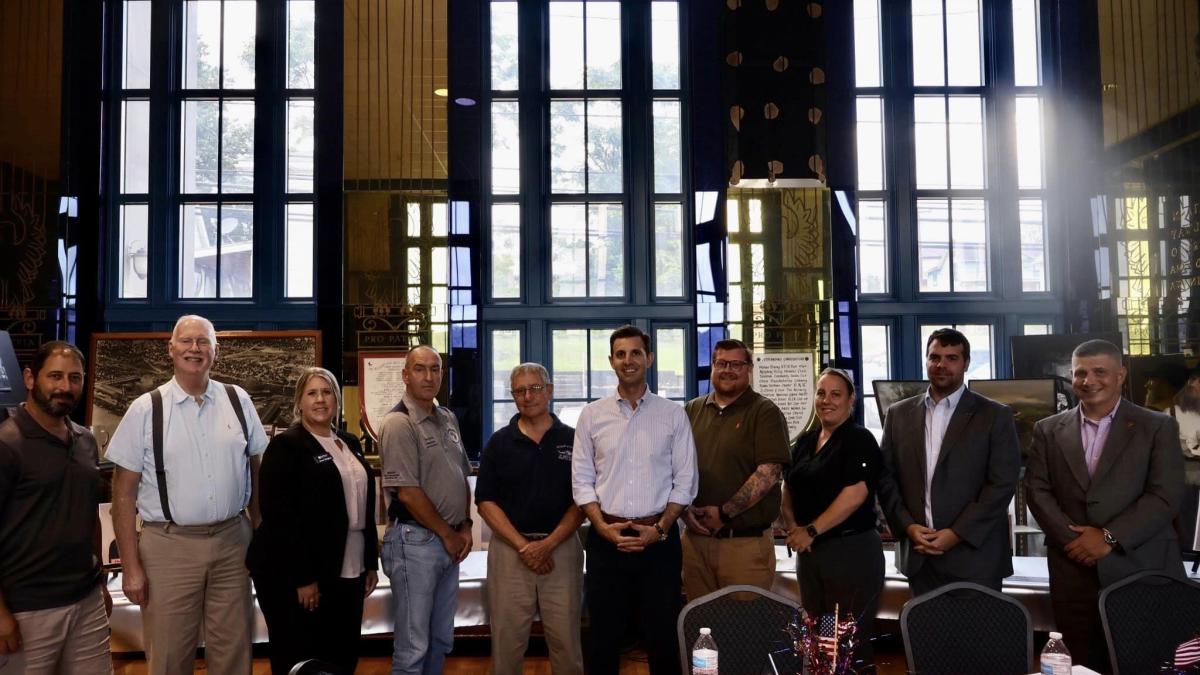 Rep. Deluzio stands with members of his Veterans Advisory Council in front of three windows