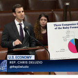 Rep. Deluzio stands behind a podium. A poster is next to him that says, "Work Hard. Play by the Rules. The American Dream."