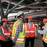 Rep. Deluzio listens as a man in a safety vest and construction hat speak to a group of people.