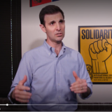 Rep. Deluzio stands in front of a sign that says "Solidarity!"