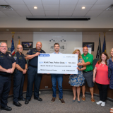 Ten people gather around a large check for a photo. 