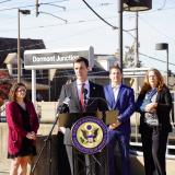 A photo of Congressman Deluzio and guests speaking at a press conference in front of the Dormont Junction T stop