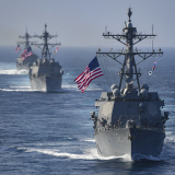 three naval ships sail on the ocean with american flags
