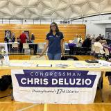 A team Deluzio member stands behind a table in a gymnasium 