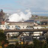 A steel factory in Western PA pumps out smoke. A train runs in front of it. 