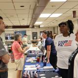 Rep. Deluzio speaks to two women behind a table with resources for veterans