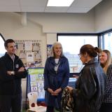 Rep. Deluzio stands next to three women in a pre school classroom. They are between two large windows. 