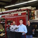 Rep. Deluzio stands in front of a fire truck and gives a speech on rail safety